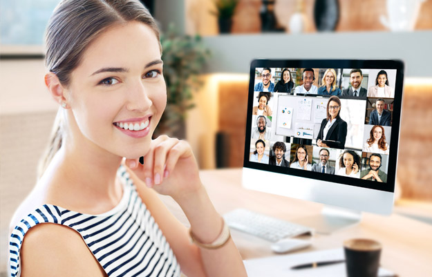 Frau sitzt am loptop in Online Konferenz mit mehreren Teilnehmern.